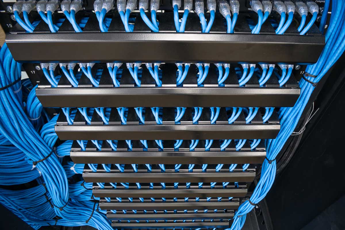 Cablaggio strutturato con cavi Ethernet blu ordinati in armadio rack aziendale.